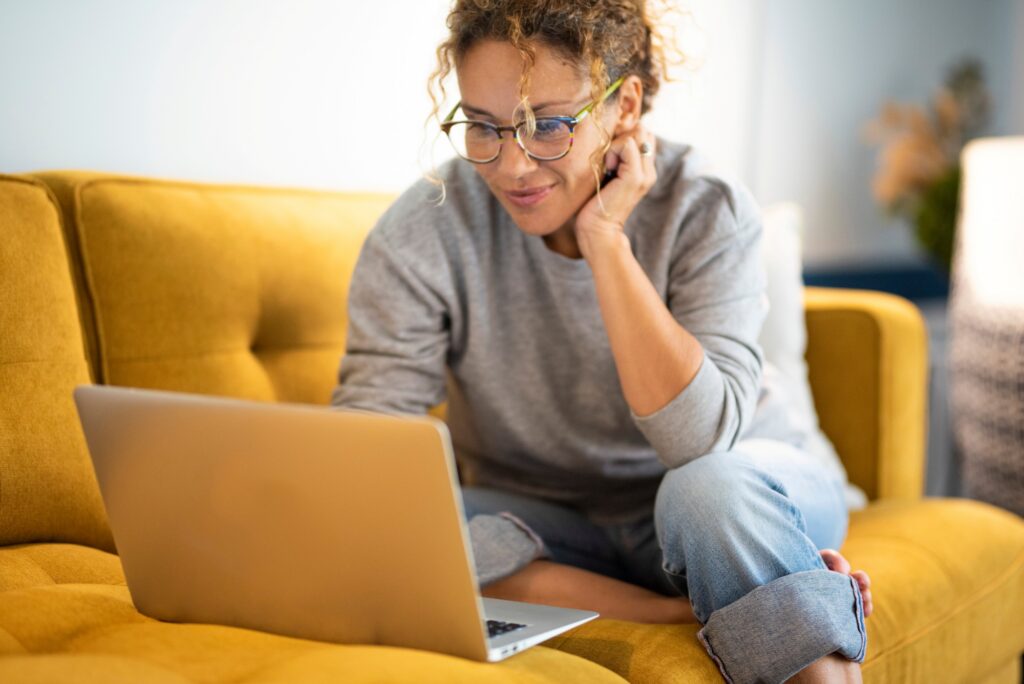 UPP member sitting on a couch at home while on here laptop looking at the members site.