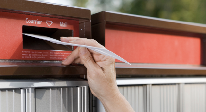 Person dropping a letter in a mailbox