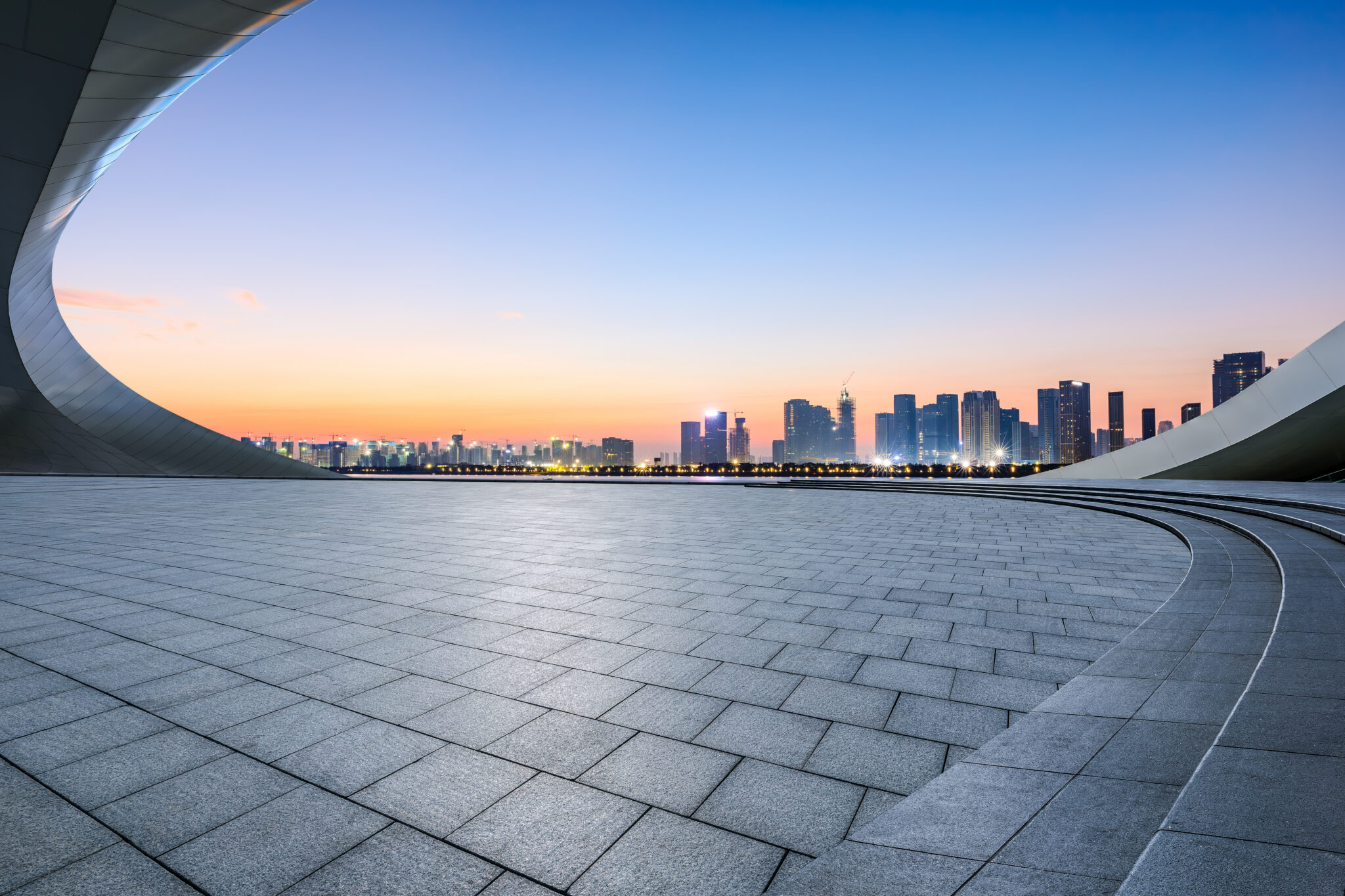 City skyline at dusk framed by curved modern architecture.