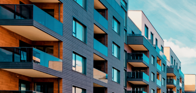 Modern apartment building with glass balconies and grey exterior siding.
