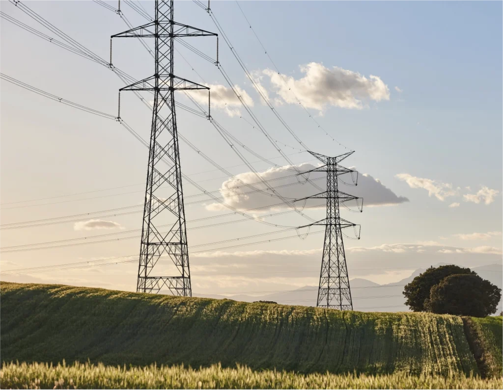 Power lines along a green field at sunrise