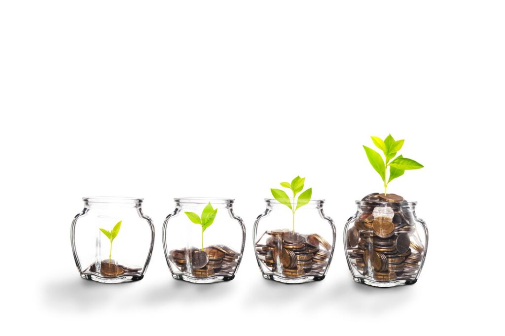 A row of 4 money jars each filled to different amounts with coins symbolizing financial growth over time.